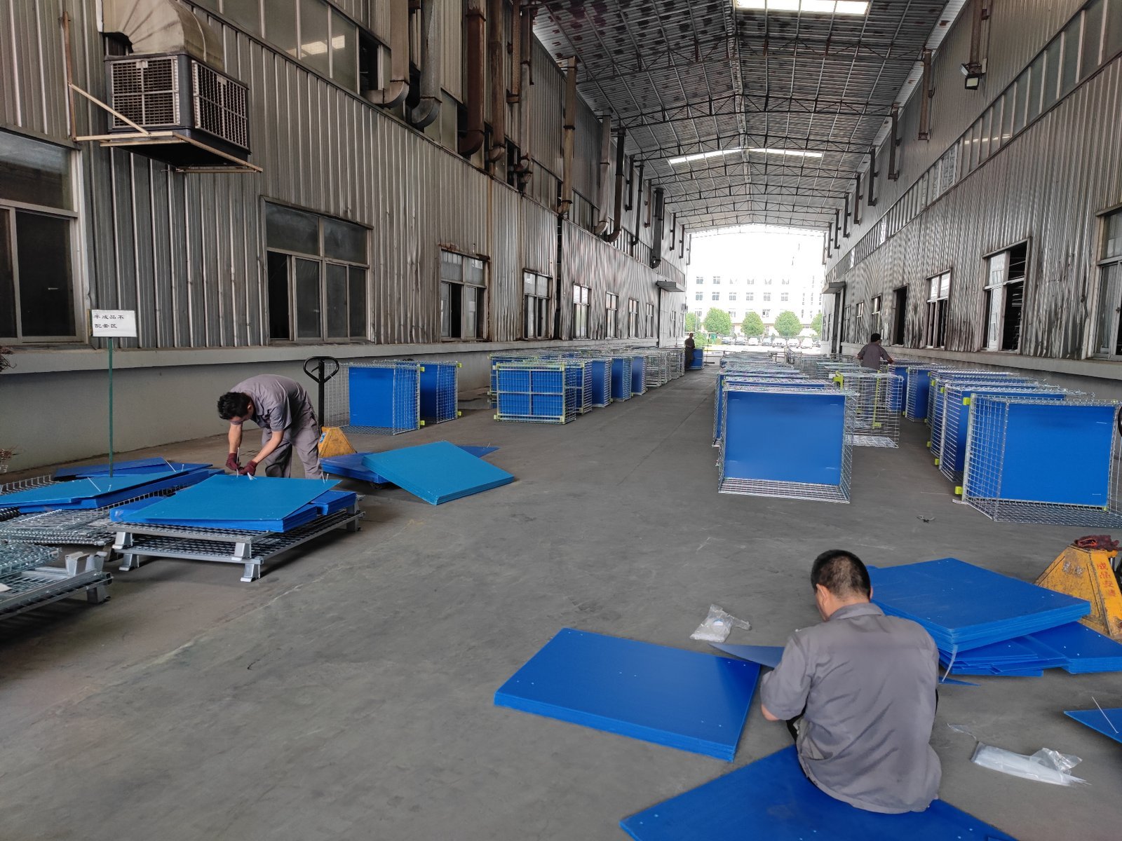 Factory workers fitting hollow-board lining panels into wire containers